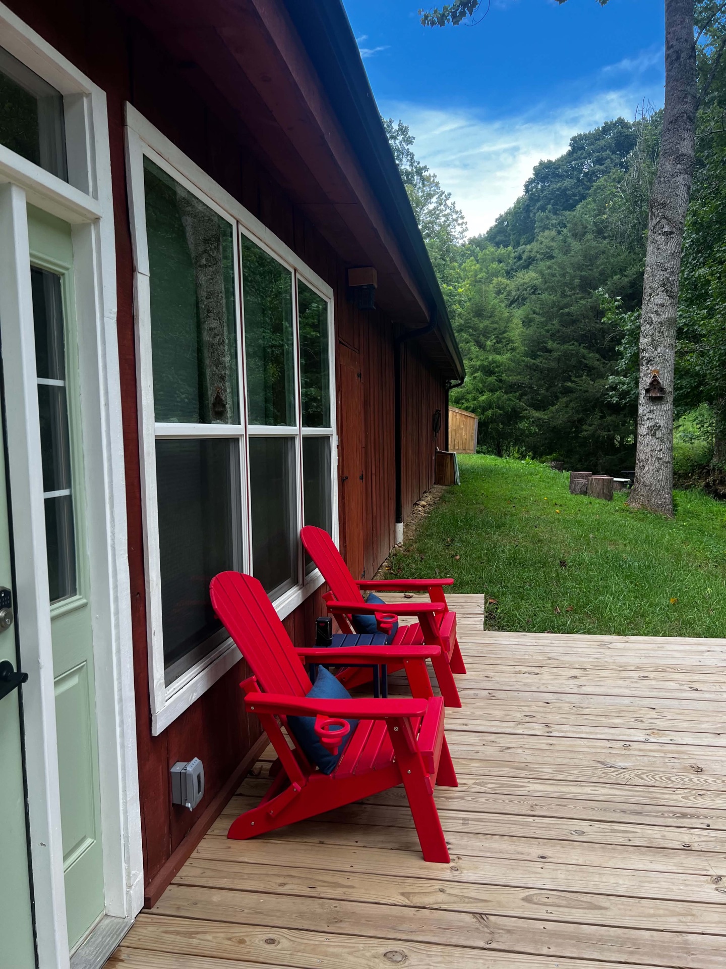 Sunny patio with red Adirondack chairs beside the stream